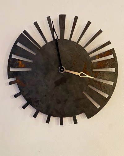 A clock, cut out from a steel plate. It's rusty. It looks like an ancient artefact with a deeper meaning. 