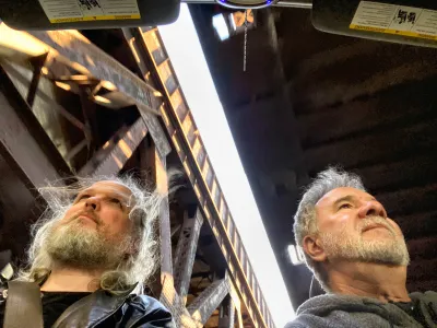 I was fascinated by the rusty railway bridges. Stephen and I were riding in his wife Donna's cabrio, with the top down. This is a wide angle shot taken from the stick shift, looking up at us and two of the bridges. 
The wide angle lens distorted our head shapes. We both look over at the street, but due to -again- the wide angle view, this seems to be in different positions.