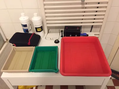 Three trays in different colors, two small, the third one big and red. They will hold the chemicals for the first step: black and white developer, stopbath and rinse with water.
