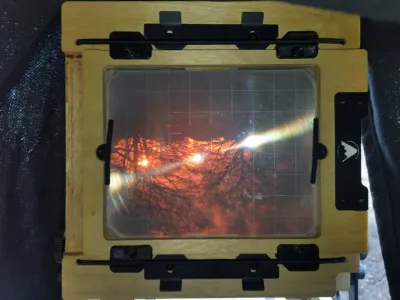 A view through the viewfinder of my 4x5. You can see the plywood filmholder clamp, with the ground glass in it. There is a fresnel lens over the ground glass, but still is strong vignetting. There is an orange cast over the image: that is my color correction that I mounted into the lens.