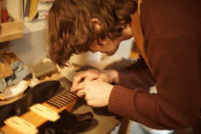 Pelle bent over the bass, working on it.