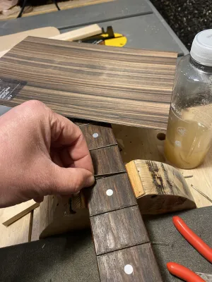 Cutting strips of fineer out of a thin sheet, to fill the gaps with, that used to accommodate the frets.