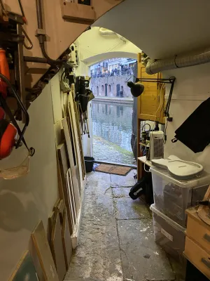 The exit of the workplace offers a great view over the old canal. The little corridor of 2 meters to the door has spare wood on one side, and a bare guitar body on some crates on the other.